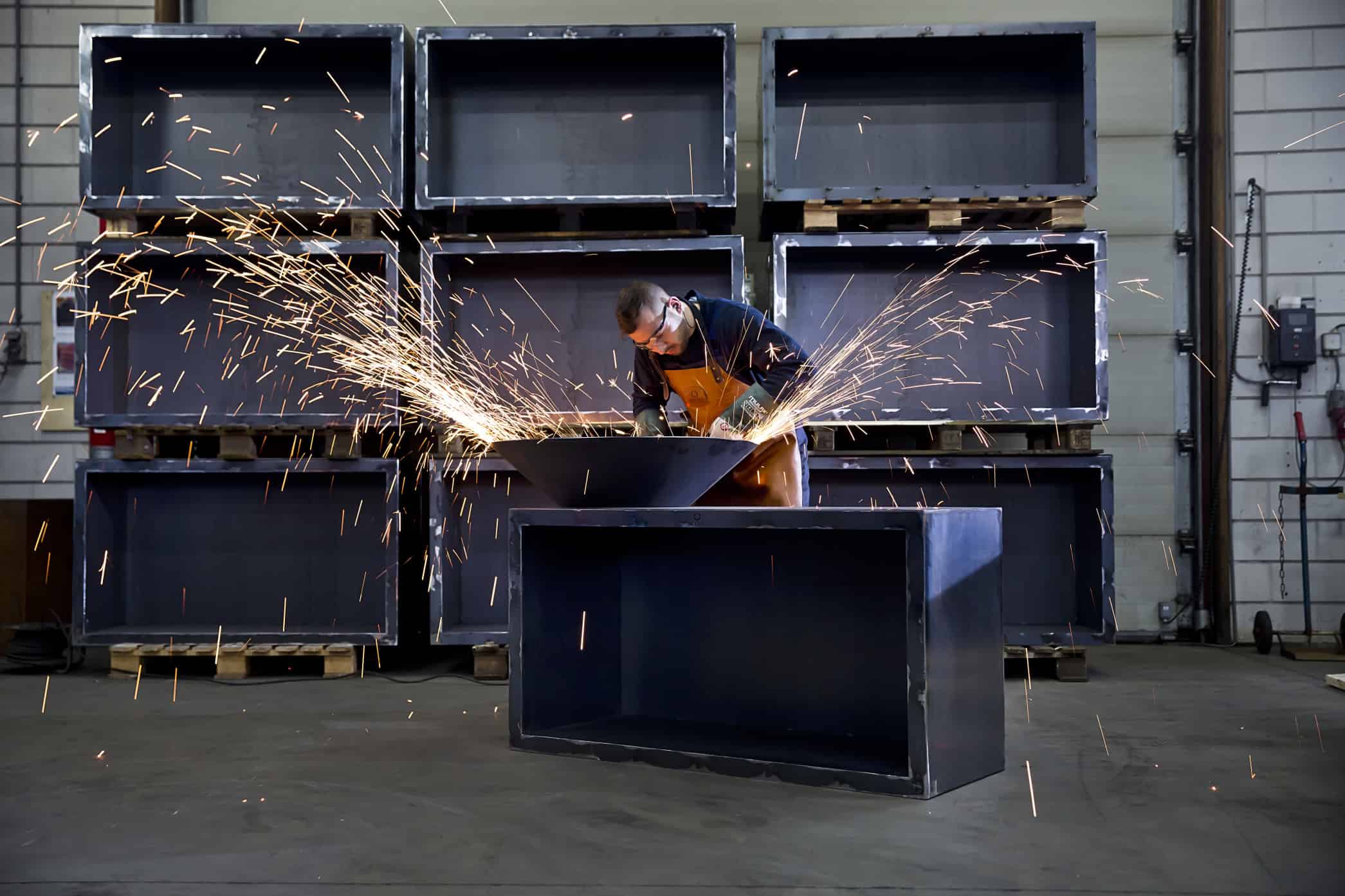 Vakman lasert en snijdt grote metalen onderdelen in een industriële werkplaats.